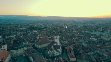 Romanya 'nın Sibiu kentinin ortaçağ kent merkezinin görüntüleri. Video, Katedral 'in yörüngesinde uçarken, panoramik bir görüntü için kamera seviyesiyle gün batımında bir İHA' dan çekildi..