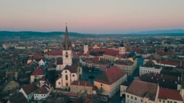 Romanya 'nın Sibiu kentinin ortaçağ kent merkezinin görüntüleri. Video, Katedral 'in yörüngesinde uçarken, panoramik bir görüntü için kamera seviyesiyle gün batımında bir İHA' dan çekildi..
