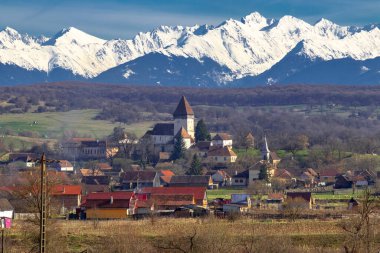 Romanya 'nın Sibiu kentindeki Hosman kentindeki güçlendirilmiş kilisenin fotoğrafları, arka planda Fagaras dağları ile birlikte gün ortasında çekildi..