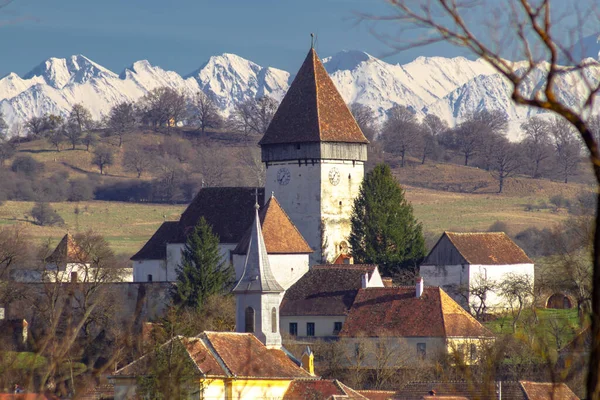 Romanya 'nın Sibiu kentindeki Hosman kentindeki güçlendirilmiş kilisenin fotoğrafları, arka planda Fagaras dağları ile birlikte gün ortasında çekildi..
