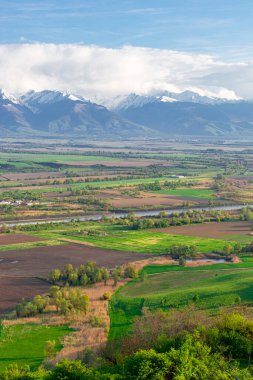 Arka planda kırsal ekinleri, gölü ve Fagaras dağları olan güzel Transilvanya manzarasının fotoğrafları. Fotoğraf geniş açı mercek kullanılarak daha yüksek bir yerden çekildi..