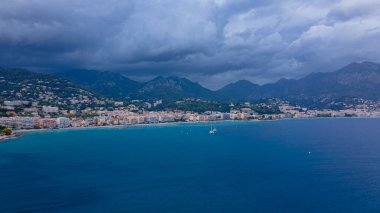 Menton, Fransa 'daki Fransız Rivierası' nın hava görüntüsü. Fotoğraf, daha yüksek bir irtifada, körfezin yukarısından, arka planda fırtınalı bir havada şehir ve dağlarla çekilmiş..