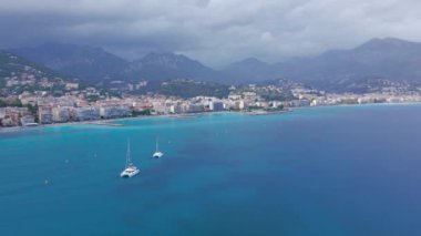 Menton, Fransa 'daki Fransız Rivierası' nın hava görüntüsü. Görüntüler daha yüksek bir irtifada, körfezin yukarısından, arka planda fırtınalı bir havada şehirle ve dağlarla çekilmiş..