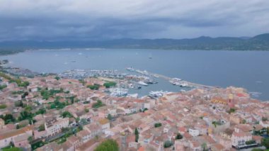 Saint-Tropez 'deki marinanın havadan görüntüsü. Görüntüler, bulutlu bir günde, arka planda körfez olan bir dron tarafından çekildi. Lüks yatlar ve rıhtımdaki tekneler kuşların gözünün önünde..