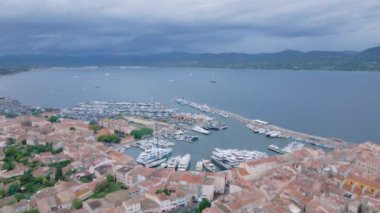 Saint-Tropez 'deki marinanın havadan görüntüsü. Görüntüler, bulutlu bir günde, arka planda körfez olan bir dron tarafından çekildi. Lüks yatlar ve rıhtımdaki tekneler kuşların gözünün önünde..