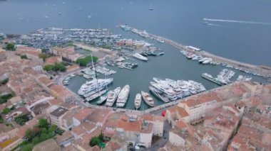 Saint-Tropez 'deki marinanın havadan görüntüsü. Görüntüler, bulutlu bir günde geriye doğru uçarken arka planda körfezle birlikte bir İHA tarafından çekildi. Lüks yatlar ve rıhtımdaki tekneler kuşların gözünün önünde..