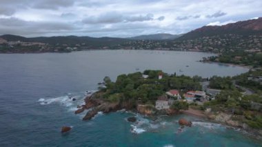Fransız Rivierası 'ndaki Agay hangarının havadan çekilmiş videosu. Görüntülerde Agay deniz feneri ve arka planda dağlar olan körfez manzarası görülebilir. Video bulutlu bir günde çekilmiş..