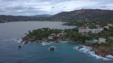 Fransız Rivierası 'ndaki Agay hangarının havadan çekilmiş videosu. Görüntülerde Agay deniz feneri ve arka planda dağlar olan körfez manzarası görülebilir. Video bulutlu bir günde çekilmiş..