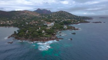 Fransız Rivierası 'ndaki Agay hangarının havadan çekilmiş videosu. Görüntülerde Agay deniz feneri ve arka planda dağlar olan körfez manzarası görülebilir. Video bulutlu bir günde çekilmiş..