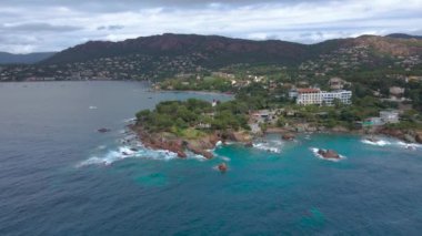 Fransız Rivierası 'ndaki Agay hangarının havadan çekilmiş videosu. Görüntülerde Agay deniz feneri ve arka planda dağlar olan körfez manzarası görülebilir. Video bulutlu bir günde çekilmiş..