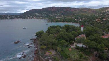 Fransız Rivierası 'ndaki Agay hangarının havadan çekilmiş videosu. Görüntülerde Agay deniz feneri ve arka planda dağlar olan körfez manzarası görülebilir. Video bulutlu bir günde çekilmiş..