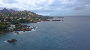 Fransız Rivierası 'ndaki Agay hangarının havadan çekilmiş videosu. Görüntülerde Agay deniz feneri ve arka planda dağlar olan körfez manzarası görülebilir. Video bulutlu bir günde çekilmiş..