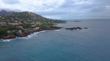 Fransız Rivierası 'ndaki Agay hangarının havadan çekilmiş videosu. Görüntülerde Agay deniz feneri ve arka planda dağlar olan körfez manzarası görülebilir. Video bulutlu bir günde çekilmiş..