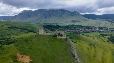 Romanya 'daki Trascau Ortaçağ Kalesi kalıntılarının hava fotoğrafı. Fotoğraf, arka plandaki dağlarla güçlendirmenin panoramik görüntüsü için kamera seviyesine sahip bir drondan çekildi..