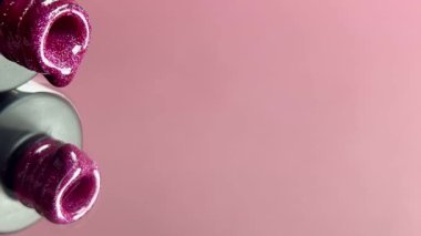 Pembe arka plandaki açık bir şişeden damlayan pembe bir tırnak cilası. Reklam jeli ojesi parlak bir renk. Yavaşça jöle ojeli damlalar. Yakın plan..
