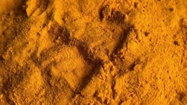 Turmeric powder rotating background. Close up.