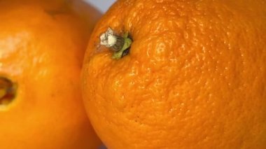 Whole orange fruits on white background. Close-up. Slow motion.
