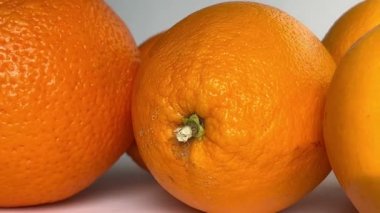 Whole orange fruits on white background. Close-up. Slow motion.