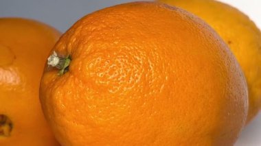 Whole orange fruits on white background. Close-up. Slow motion.