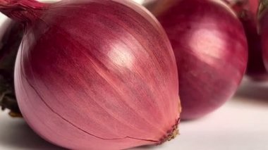 Fresh whole purple onions on white background. Close-up. Slow motion.