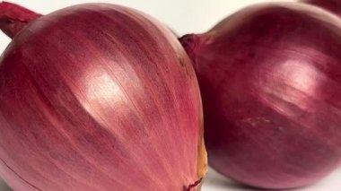 Fresh whole purple onions on white background. Close-up. Slow motion.