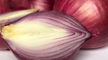 Fresh whole purple onion and cut in half on white background. Close-up. Slow motion.