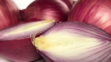 Fresh whole purple onion and cut in half on white background. Close-up. Slow motion.