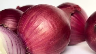 Fresh whole purple onion and cut in half on white background. Close-up. Slow motion.