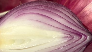 Fresh whole purple onion and cut in half on white background. Close-up. Slow motion.