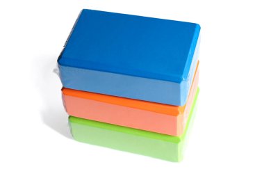 Beyaz arka planda üç farklı renkte yoga bloğu var. Fitness ekipmanı kavramı.