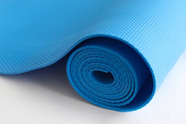 Beyaz bir arkaplanda mavi bir yoga minderi. fitness ekipmanı önlemi.