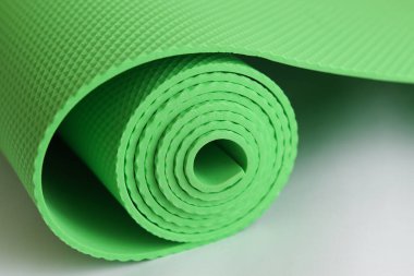 Beyaz arka planda izole edilmiş yeşil yoga minderi. fitness ekipmanı önlemi.