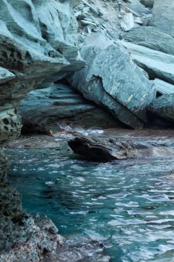 Girit adasında pürüzsüz taş oluşumları ve berrak turkuaz suların yer aldığı sakin bir kayalık kıyı manzarası. Doğal dokular ve renkler Akdeniz 'in dokunulmamış güzelliğini yansıtıyor..