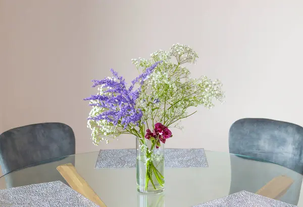 A bouquet of gypsophila flowers in a transparent glass vase on a kitchen table on a light background.