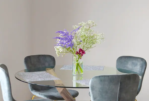 A bouquet of gypsophila flowers in a transparent glass vase on a kitchen table on a light background.