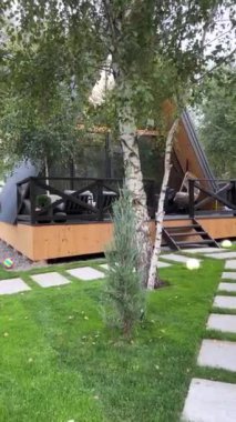 Suçu House 'a at. Modern yeni çerçeve kır evi karışık bir ormanda kameranın önünde, ağaçların arkasında duruyor..