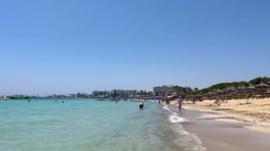 Ayia Napa, Kıbrıs - 6 Haziran 2023: Mavi gökyüzü ve beyaz bulutlarla güneşli bir gün. Otellerin panoramik manzarası, mavi göl ve kıyı şeridi..