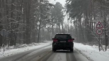 Karlı havada, kır yolunda bir araba. Kış mevsiminde ormanın ortasındaki yol. Donmuş orman ve lüks sedan boyunca yol.