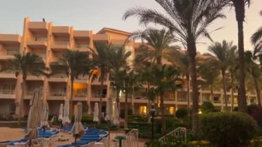Hurghada, Mısır - 11 Kasım 2024: Tropik palmiye ağaçları ve geceleri yüzme havuzu olan otel, Hurghada, Mısır.