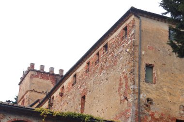 Toskana, İtalya - 25 Kasım 2024: Yıpranmış taş duvarları, sarmaşık sarmaşıkları ve sakin bir kırsal zemin ile sahip, ortaçağ mimarisi ve cazibesi sergilenen bir Toskana şatosu oteli.