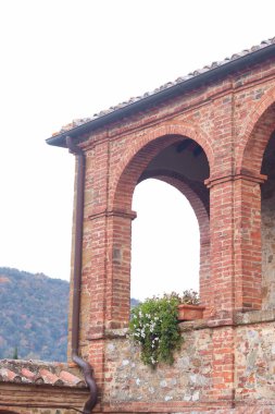 Trequanda, İtalya - 25 Kasım 2024: Tuscany 'de 13. yüzyıl ortaçağ şatosu olan büyüleyici tarihi bir binanın bölgesi, şimdi ise bir otel. Kırsal taş duvarlar, kemerli pencereler.