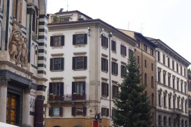 Floransa, İtalya 'da klasik mimarinin sokak manzarasında, kilisenin ön cephesinde kepenkleri kapalı ve ayrıntılı heykeller bulunan tarihi binalar yer alıyor..