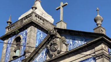 Portekiz, Porto 'da Capela das Almas. Mavi ve beyaz azulejo fayansları, taş bir haç ve temiz bir gökyüzünün altında çan kulesi olan tarihi bir kilise. Ünlü bir dini ve kültürel eser..