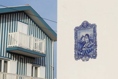 Aveiro, Portekiz - 20 Şubat 2025: Geleneksel çizgili bir ev ve bebek İsa ile Aziz Anthony 'yi betimleyen mavi-beyaz bir seramik sanat eseri, büyüleyici Aveiro kıyı şehrinde fotoğraflandı..