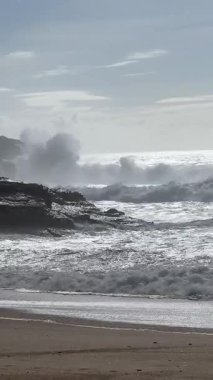 Güçlü okyanus dalgaları Praia do Norte, Portekiz 'in kayalıklarına çarpıyor ve üzerinde ünlü deniz feneri duruyor. Dramatik gökyüzü ve sisli hava nefes kesici bir kıyı manzarası yaratır..