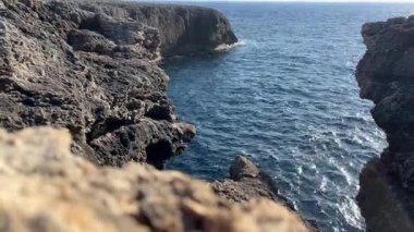 Berrak mavi suyu olan engebeli bir sahil kayalığı, parlak bir gökyüzüne karşı kurulmuş, Kaptan d Artrutx, Menorca 'nın doğal güzelliğini gözler önüne seriyor..