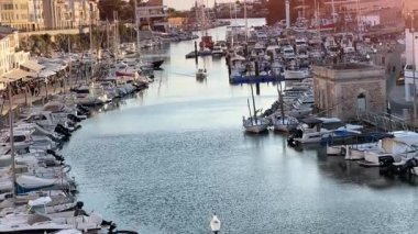 Gün batımında Ciutadella de Menorca 'da büyüleyici bir liman sahnesi. Demirlemiş tekneler, tarihi binalar ve hareketli bir gezinti alanı ile çevrili sakin bir su yolunda..