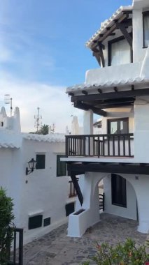 Geleneksel beyazlatılmış binibeca Vell, Menorca evleri, panjurları ve mavi gökyüzünün altında ahşap balkonları var. Huzurlu mimarisi olan büyüleyici bir Akdeniz köyü..