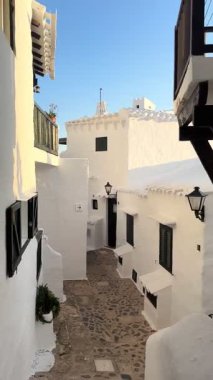 Geleneksel beyazlatılmış binibeca Vell, Menorca evleri, panjurları ve mavi gökyüzünün altında ahşap balkonları var. Huzurlu mimarisi olan büyüleyici bir Akdeniz köyü..