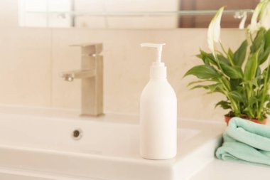 El yıkama, beyaz lavaboda sabunla ya da kremayla şişeyi düzenleme, yeşil bitki. Eko Konsept Hijyen